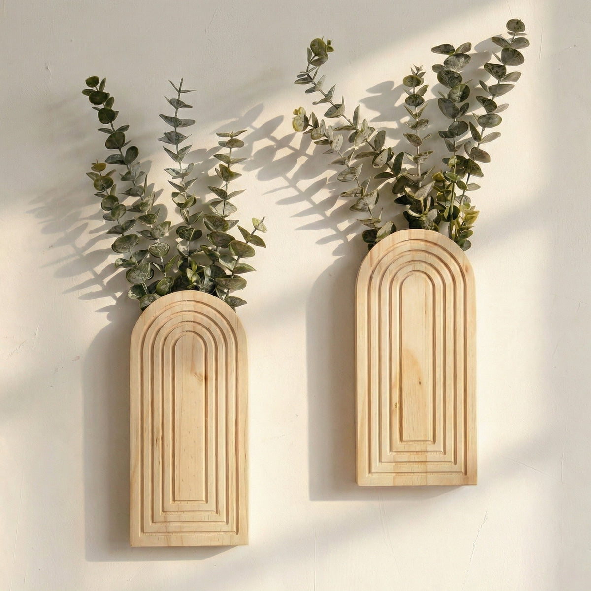 Two wooden wall planters with greenery on a light background