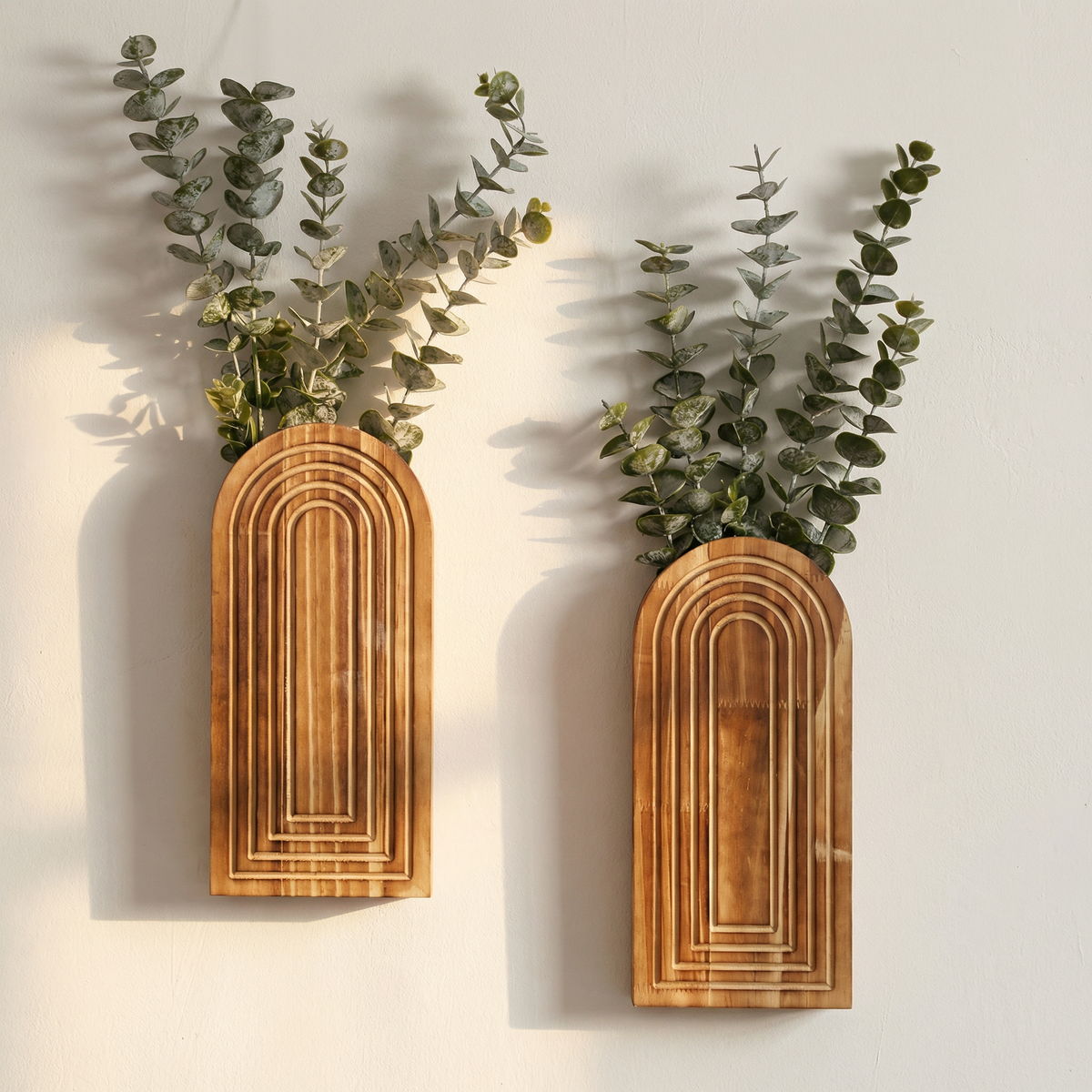 Two wooden wall planters with greenery on a light background