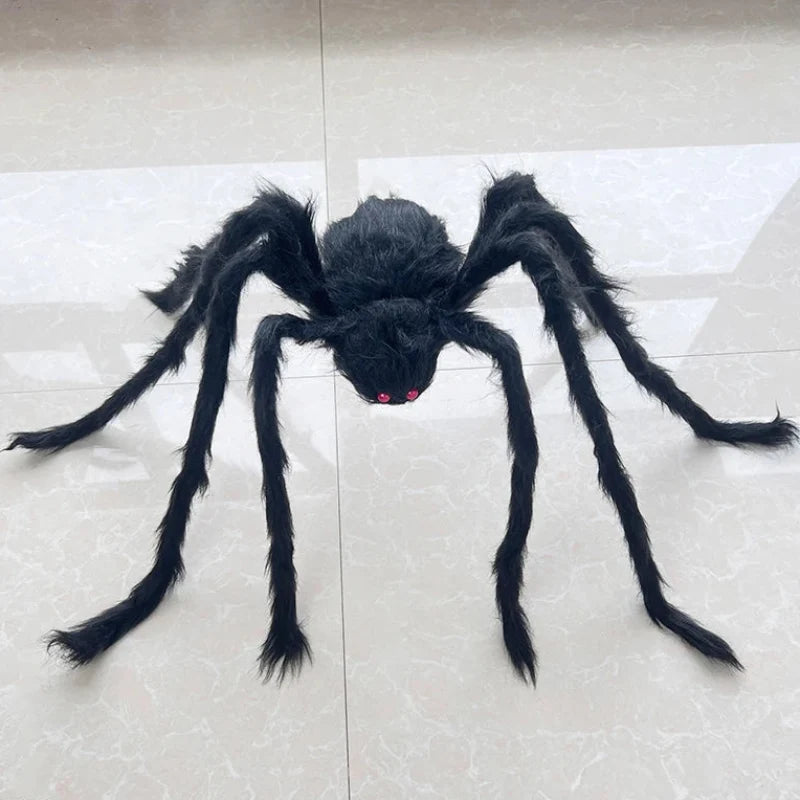 A large black hairy spider toy with red eyes, displayed on a light beige tiled floor.