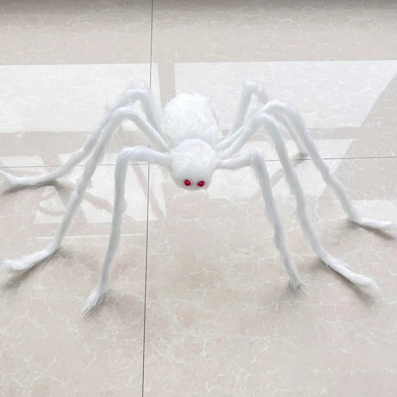 A white faux-fur spider Halloween decoration with red eyes, placed on a light beige tiled floor.